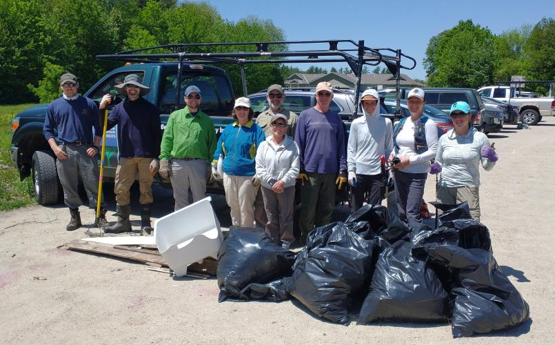 Volunteers and staff pose with trash bags after a cleanup at Champlin Forest.