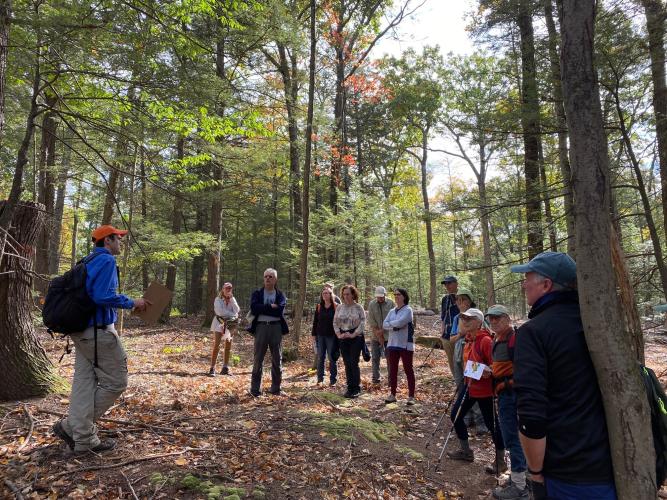 Hiking group discuss climate change resiliency, carbon sequestration and carbon storage with field forester Gabe Roxby (left) in a hemlock and red oak forest at Heald Forest Reservation