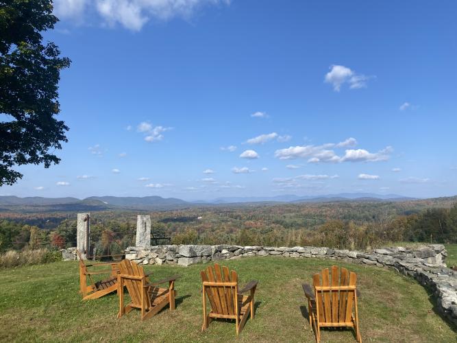 Wood Adirondack chairs sit with views of the White Moutains.