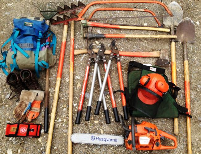 Forestry tools including gloves and a timber jack are organized on the ground.