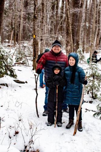 A family poses together on a snowy trail.