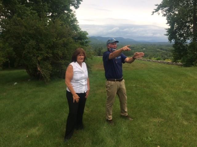 Congresswoman Kuster and SPNHF President Jack Savage standing in front of misty view of the White Mountains at The Rocks in Bethlehem.