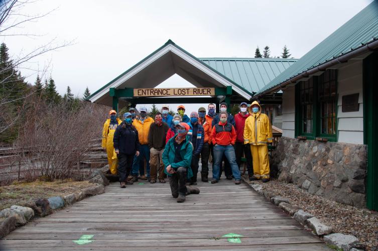A group of volunteers in rain gear poses by the entrance to Lost River Gorge.