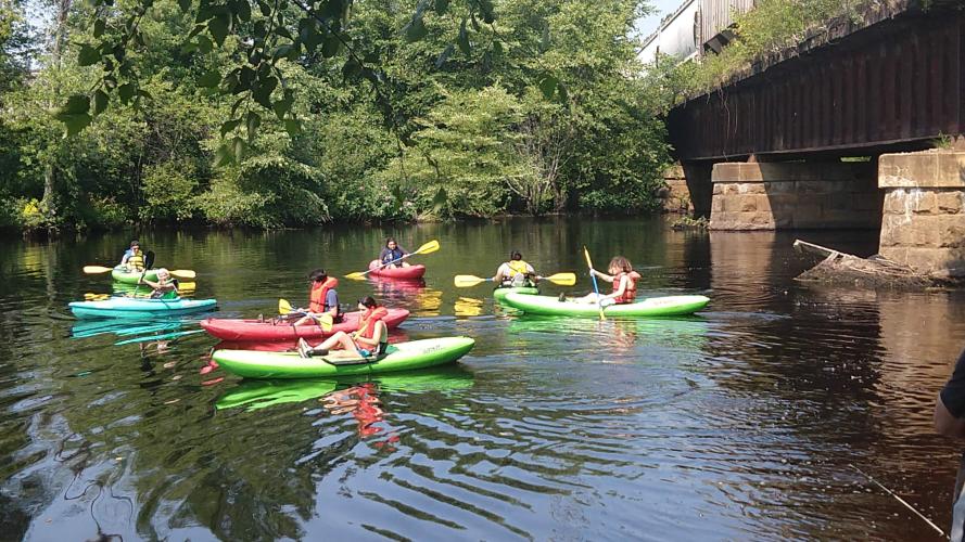Young paddlers gather in kayaks on the river.