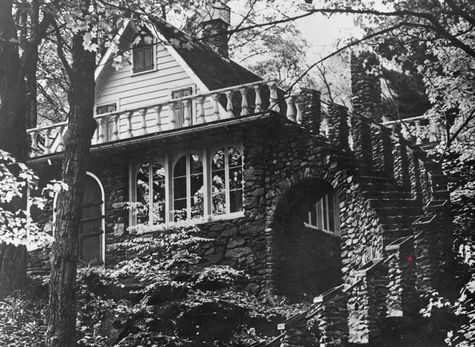 A black and white photo of Madame Sherri's original house with a winding outdoor stone staircase.
