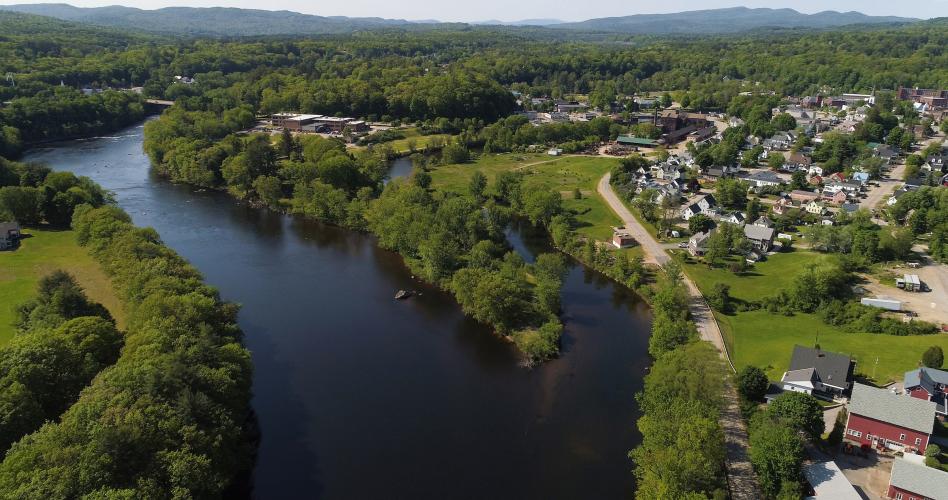 A winding blue river passes the small houses and red barns that make up Franklin, New Hampshire.