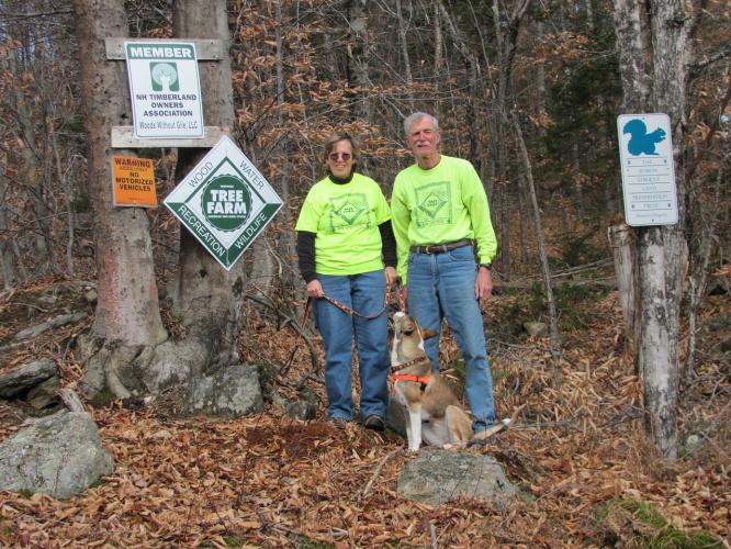 Ann and March Davis pose in front of their Tree Farm with their dog.