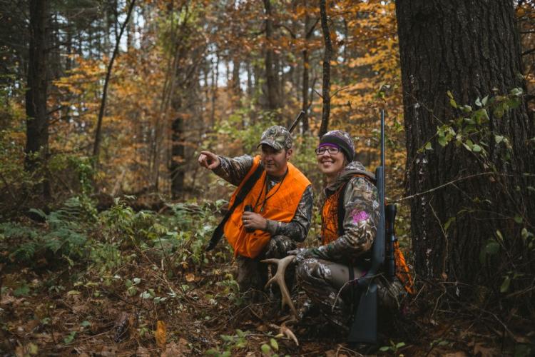 Two hunters in blaze orange clothing in NH autumn woodland scene