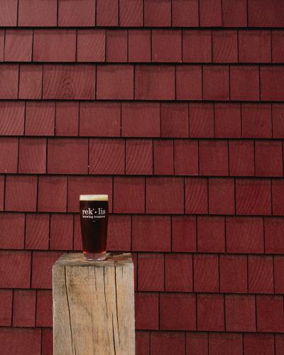 A pint of Rocks Red Ale sits on a stool in front of the renovated barn.